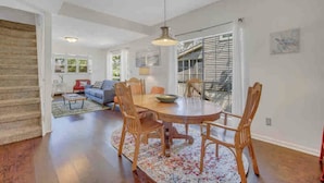 A spacious living room with a large wooden dining table, comfortable seating, and a staircase leading to an upper level. - The Fairy Tern, PRIVATE/ONE-OF-A-KIND 4bd/3bth on Tybee's North End (Tybee Island)