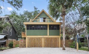 A two-story building with a balcony, a fenced driveway, and a palm tree. - The Fairy Tern, PRIVATE/ONE-OF-A-KIND 4bd/3bth on Tybee's North End (Tybee Island)