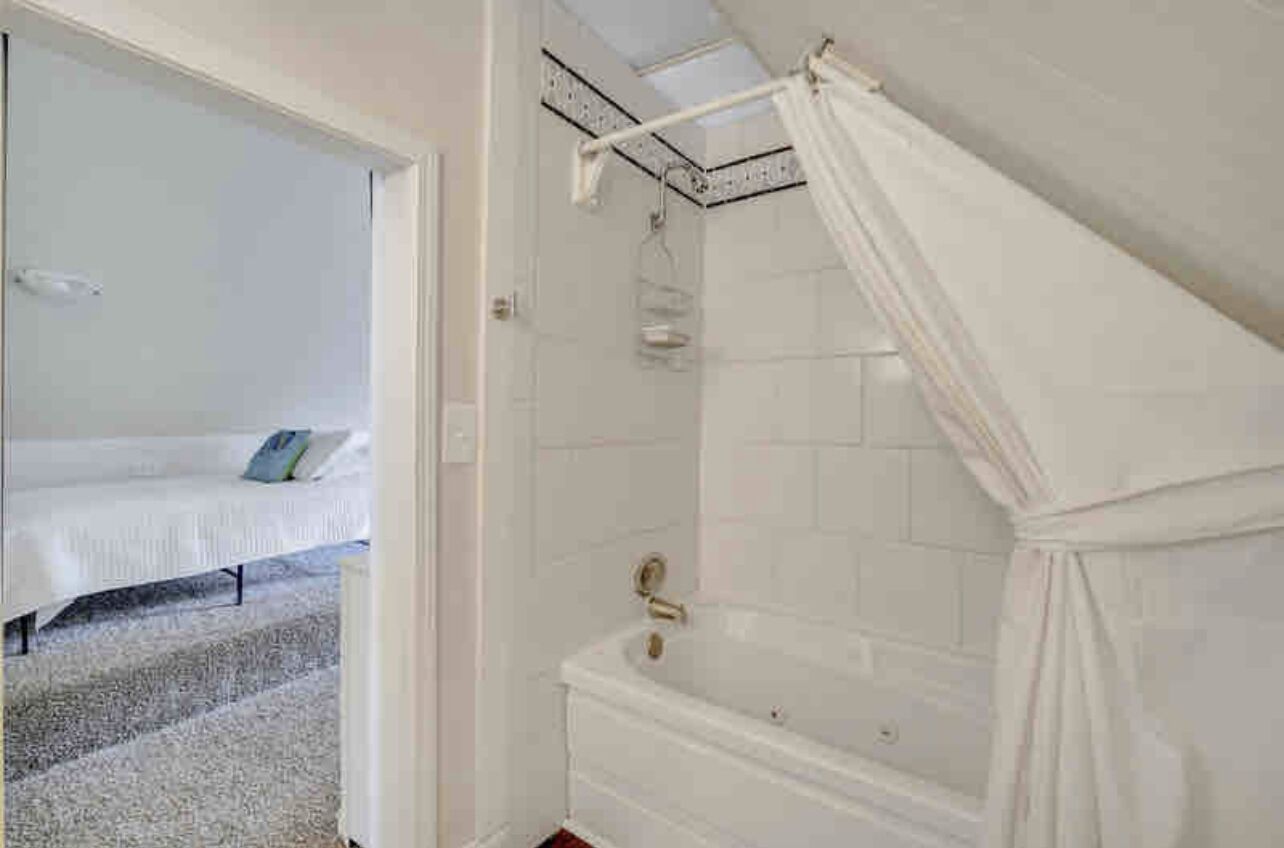 Une chambre avec un lit, une salle de bain avec une baignoire et une douche.