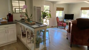 A spacious living area with a kitchen, a dining table, and a TV. - Colony Haven in the Oaks (Atascadero)