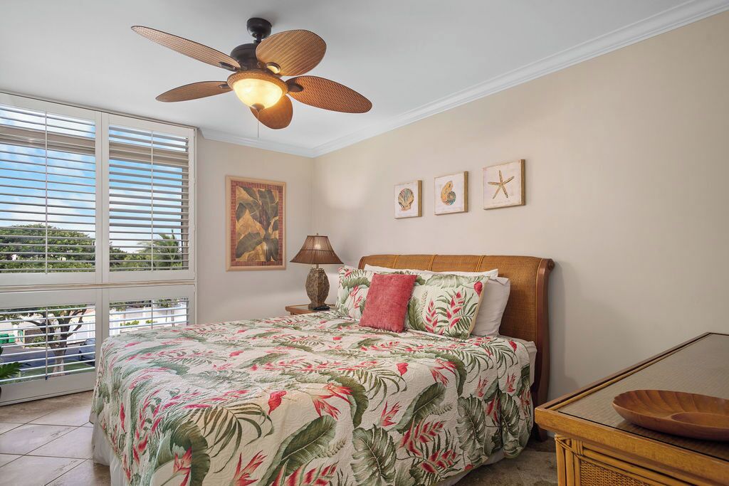 Quarto com cama, ventoinha no teto, janela com cortinas e decoração nas paredes.