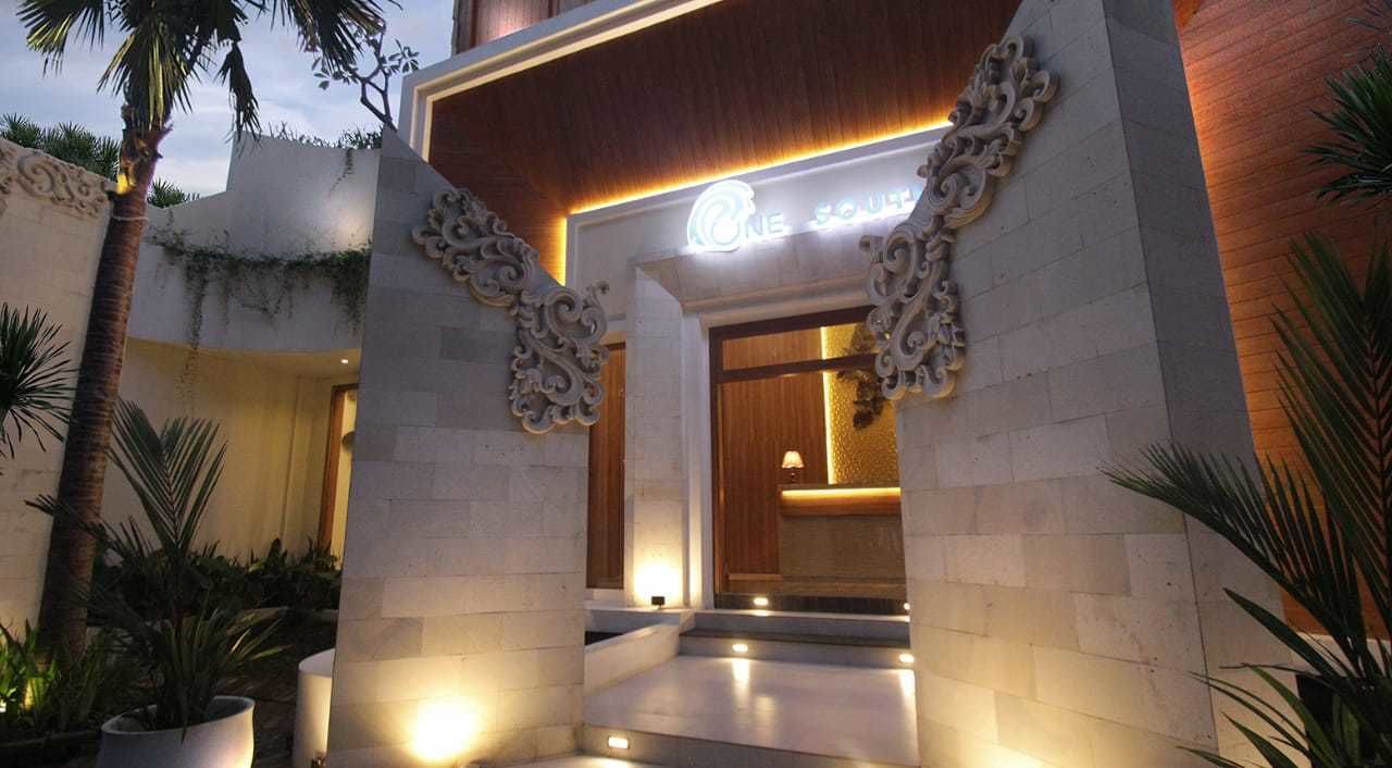 Een hotelingang met een modern ontwerp, met een opvallend bord en decoratieve zuilen.