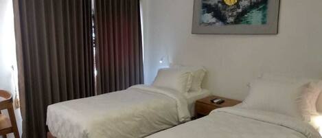 Una habitación de hotel con dos camas, un escritorio y un cuadro en la pared.