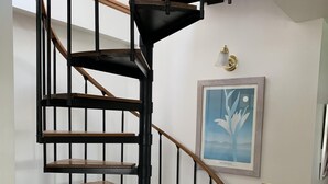A modern spiral staircase with wooden steps and black metal railings, leading to an upper floor. - Location!! Ocean views. Easy walk to beaches, restaurants, shops. Quiet street.  (Middletown)