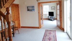 Ruime kamer met een houten trap, een flatscreen televisie en een groot raam dat natuurlijk licht biedt.