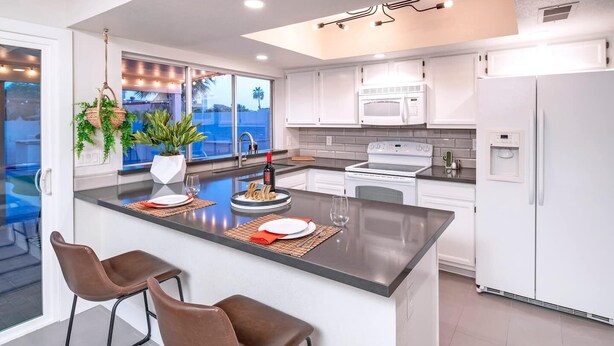 A modern kitchen with a large island, white cabinetry, and a view of the outdoors. - HOT TUB • HEATED POOL • Close to Dining & Shopping (Scottsdale)