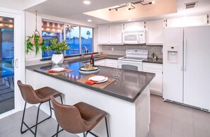 A modern kitchen with a large island, white cabinetry, and a view of the outdoors. - HOT TUB • HEATED POOL • Close to Dining & Shopping (Scottsdale)