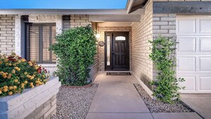 A residential house with a brick exterior, a black front door, and a garage door. - HOT TUB • HEATED POOL • Close to Dining & Shopping (Scottsdale)