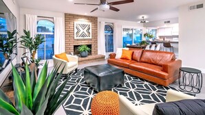 A modern living room with a fireplace, leather sofa, and a dining area. - HOT TUB • HEATED POOL • Close to Dining & Shopping (Scottsdale)