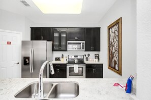 Where every culinary journey begins - our kitchen, complete with a sleek sink, is the heart of home and culinary adventures. - Resort & Pool Access 3BR Condo near Epic Universe! (orlando)