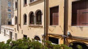 A building with arched windows and a balcony with potted plants. - Charming apartment not far from Piazza San Marco (Venezia)