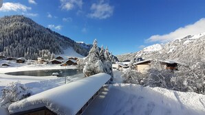 A snow-covered mountain landscape with wooden chalets and a clear blue sky. -  Exceptional Chalet –11 guests – 230 m² (74390 - CHATEL)