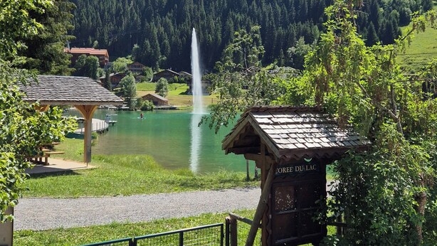 A lakeside view with a fountain, a wooden gazebo, and a mountain backdrop. -  Exceptional Chalet –11 guests – 230 m² (74390 - CHATEL)