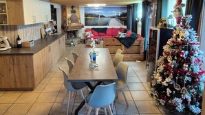 A cozy kitchen with wooden cabinets, a dining table with chairs, and a Christmas tree. -  Exceptional Chalet –11 guests – 230 m² (74390 - CHATEL)