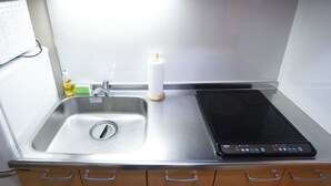 Een keuken met een roestvrijstalen spoelbak, een inbouwfornuis en een klein aanrecht.