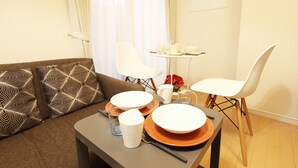 Een moderne woonkamer met een bank, een eettafel met borden en bekers, en een stoel.