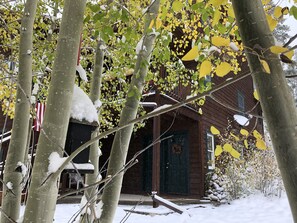 A wooden cabin with a snow-covered porch, surrounded by trees with yellow leaves. - Madge’s Studio - Pets Welcome  (Fraser)