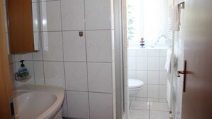A bathroom with a white sink, toilet, and shower area. - (311/1) 3-room apartment - apartment house Strandburg (Kühlungsborn)
