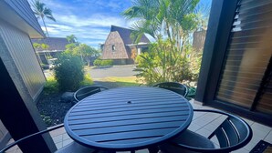 A round table with four chairs, a tiled floor, and a view of a house with a sloped roof and palm trees in the background. - One bedroom  in United States of America, Pahala (Pahala)