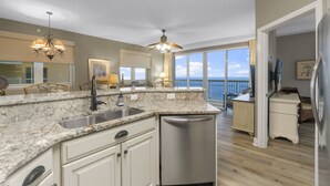 Una cocina moderna con encimeras de granito, electrodomésticos de acero inoxidable y un amplio ventanal con vistas al océano.