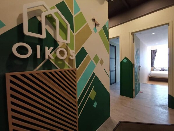 Vestíbulo de hotel con diseño geométrico en la pared y el nombre "OIKOS" bien visible.