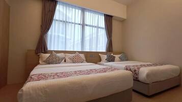 A hotel room with two beds, a large window with curtains, and a neutral color scheme.