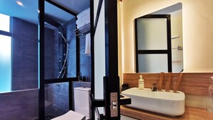A modern bathroom with a glass-enclosed shower, a white toilet, and a wooden vanity with a sink. - Oikos Poshtel (Kota Kinabalu)
