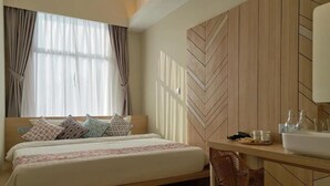 A hotel room with a bed, a desk with a sink, and a chair. - Oikos Poshtel (Kota Kinabalu)
