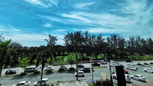 A parking lot with multiple cars and a clear sky. - Oikos Poshtel (Kota Kinabalu)