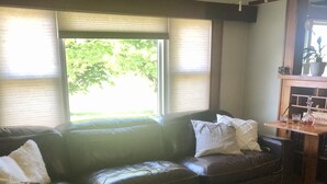 A living room with a leather sofa, a dog lying on the floor, and a wooden table with a bottle and glasses. - 4 bedroom, 116 acre Farmhouse 10 minutes from downtown  Charlevoix  (Charlevoix)