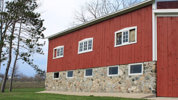A red building with stone foundation and multiple windows. - 4 bedroom, 116 acre Farmhouse 10 minutes from downtown  Charlevoix  (Charlevoix)