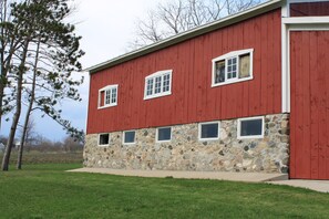 A red building with stone foundation and multiple windows. - 4 bedroom, 116 acre Farmhouse 10 minutes from downtown  Charlevoix  (Charlevoix)