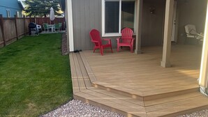 A covered patio with a wooden deck and two red chairs. - 3 bedrooms, 2 bathrooms (Sisters)