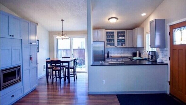 A kitchen with white cabinets, a dining area with a table and chairs, and a large window. - 3 bedrooms, 2 bathrooms (Sisters)