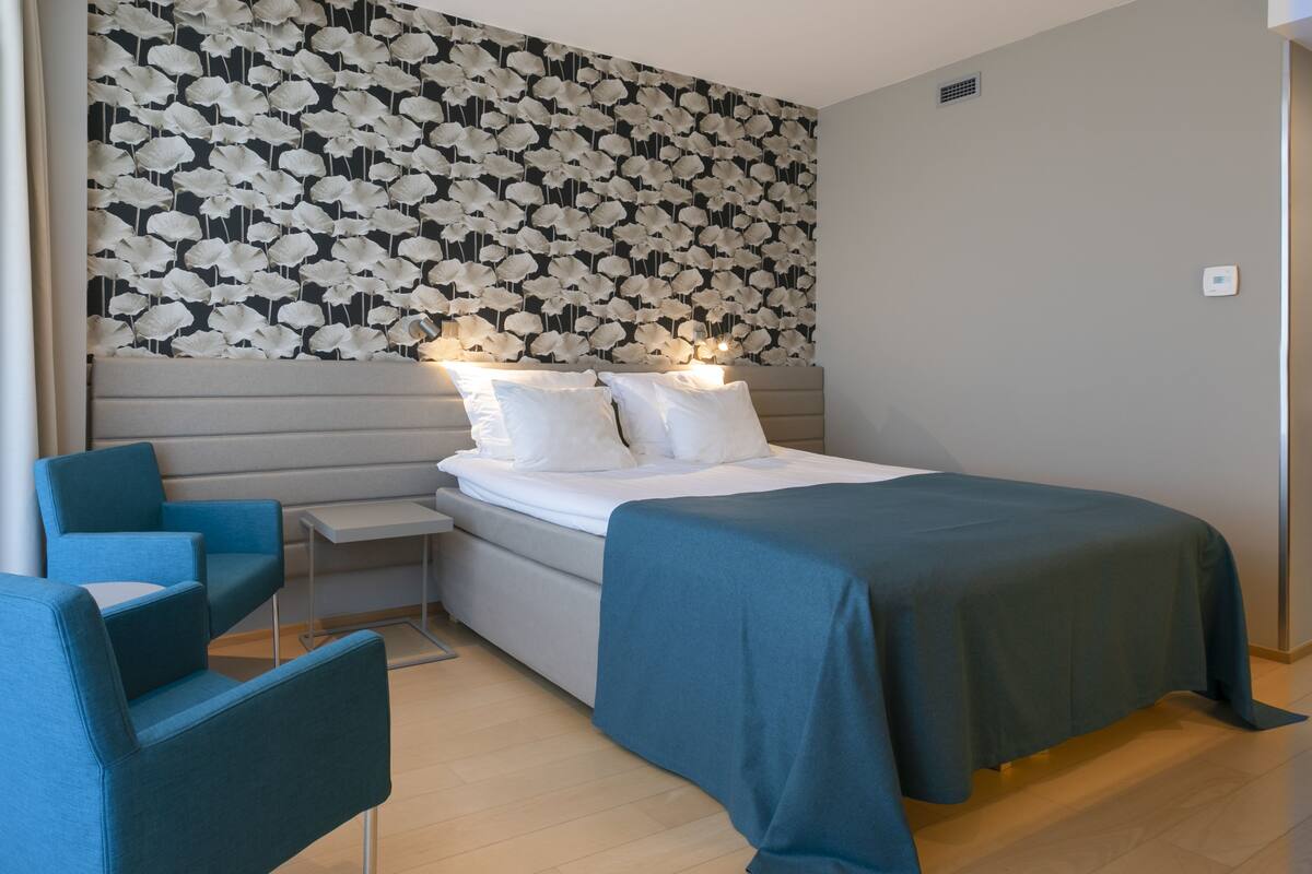 A modern bedroom with a bed, bedside tables, and a blue chair.