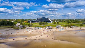 Een strand met een modern gebouw op de achtergrond, zandstranden en heldere lucht.