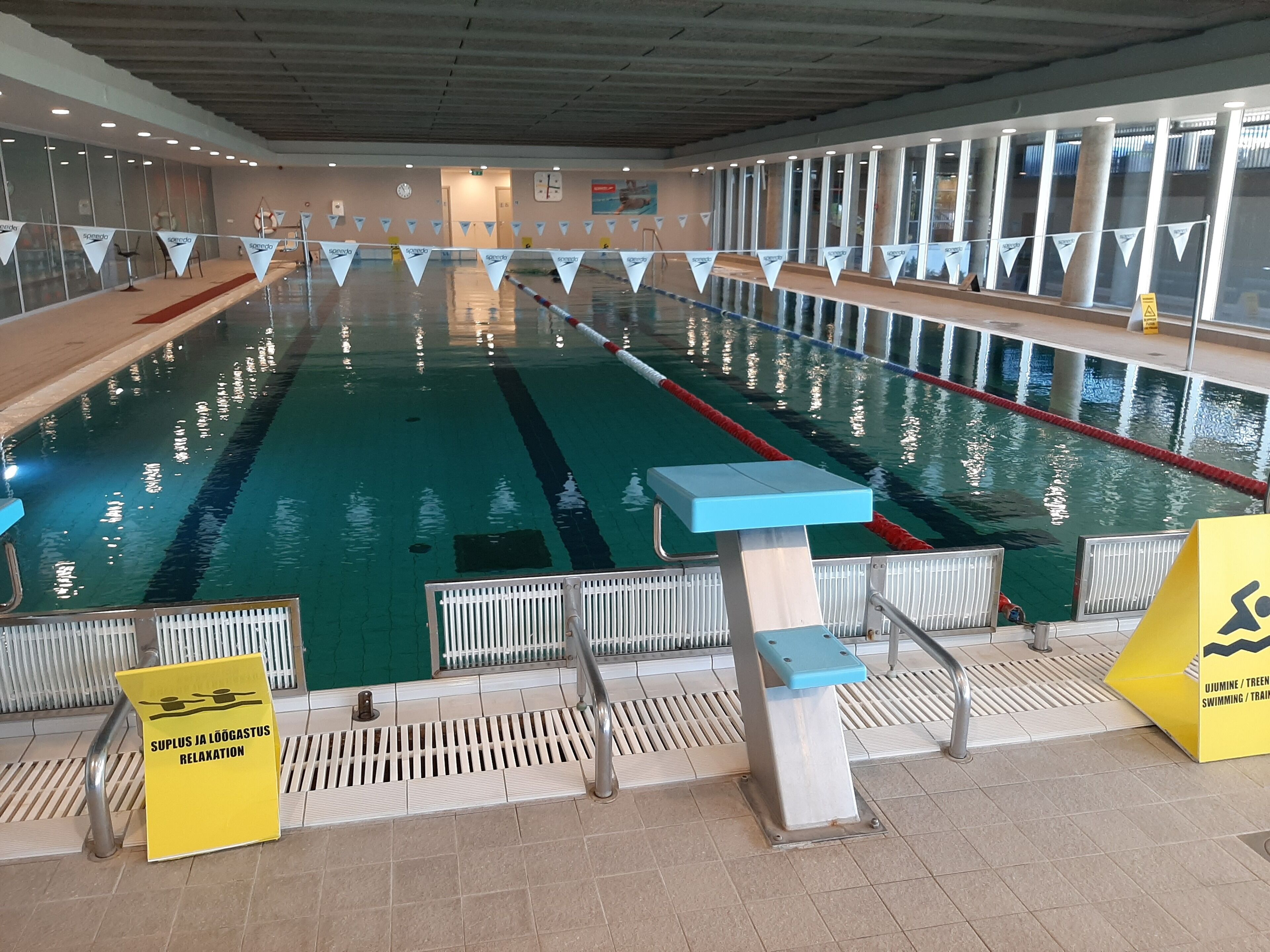 An indoor swimming pool with lanes, starting blocks, and safety signs.