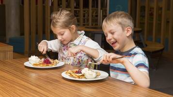 Deux enfants sont assis à une table en bois dans un restaurant dont l’intérieur présente un design moderne.