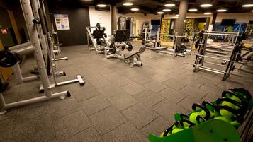 Ett gym med olika träningsmaskiner, stänger för vikter och en grön träningsboll.