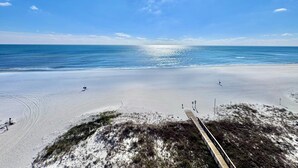 A beach with a wooden boardwalk leading to the water, sandy dunes, and a clear sky. - Time to get… 🎶 Knee deep in the water somewhere! 🎶 on island time! (Gulf Shores)