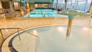 A large indoor swimming pool with a clear view of the pool area, including the pool's edge, a diving board, and a seating area with a view of the pool. - Tervis Medical Spa Hotel (Parnu)
