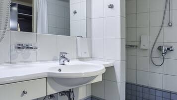 Un baño moderno con un lavamanos, espejo y ducha blancos.