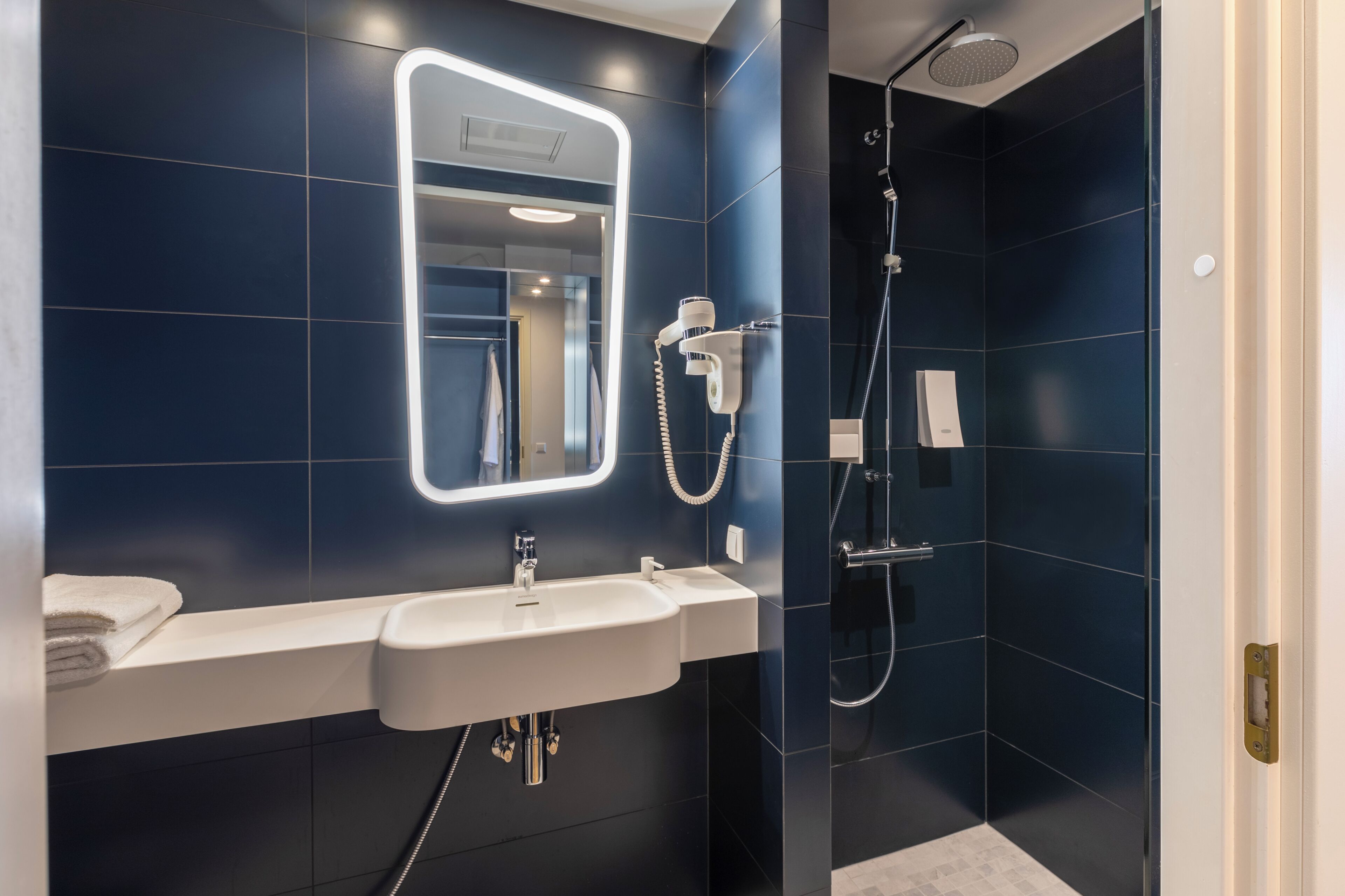 Un bany modern amb un lavabo, mirall i plat de dutxa.