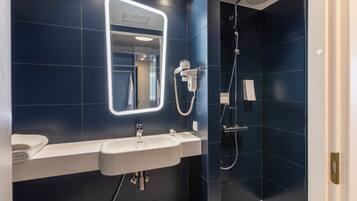 Un bany modern amb un lavabo, mirall i plat de dutxa.