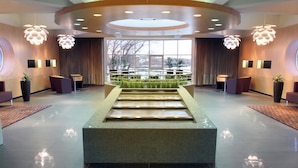 A modern lobby with a central water feature, seating areas, and large windows offering a view. - Tervis Medical Spa Hotel (Parnu)