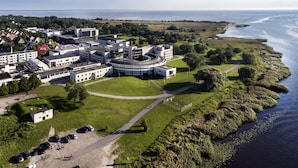 An aerial view of a coastal hotel with a central circular building, surrounded by green lawns and a parking area. - Tervis Medical Spa Hotel (Parnu)