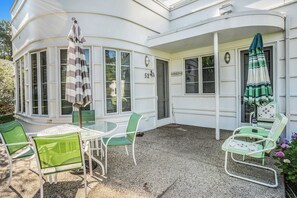 Rincón de una casa con un patio, que incluye una mesa y sillas, y dos sombrillas.