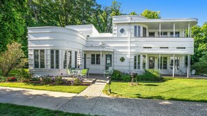 Une maison moderne à deux étages, dotée d’une façade incurvée, de grandes fenêtres et d’un porche abrité.