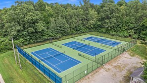 Complejo de canchas de tenis rodeado de árboles frondosos.