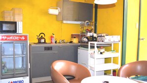 Une cuisine compacte équipée d’un réfrigérateur, d’un four à micro-ondes, d’une bouilloire et d’un petit coin repas avec deux chaises.